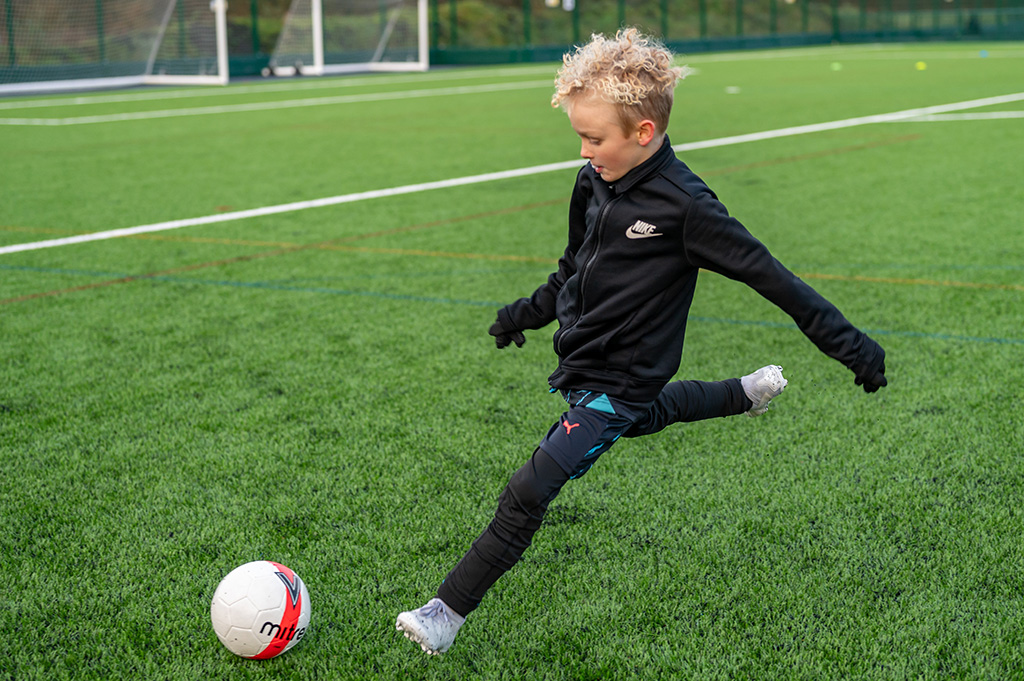 Young footballer kicking the ball during football skills training