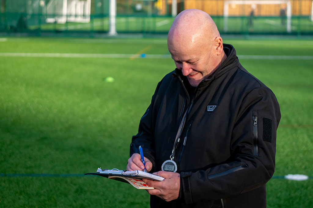 Football coach making notes during football skills training