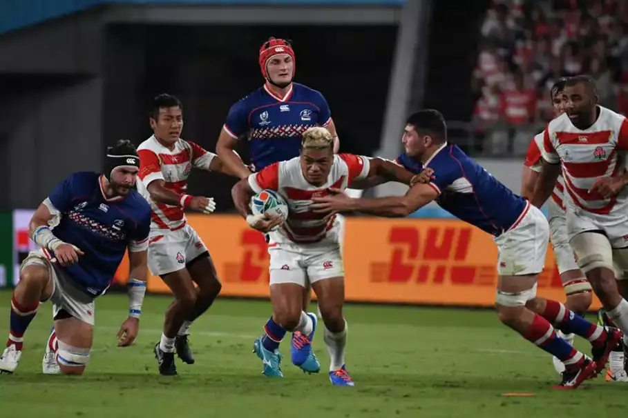 Rugby players tackling on the pitch in Japan